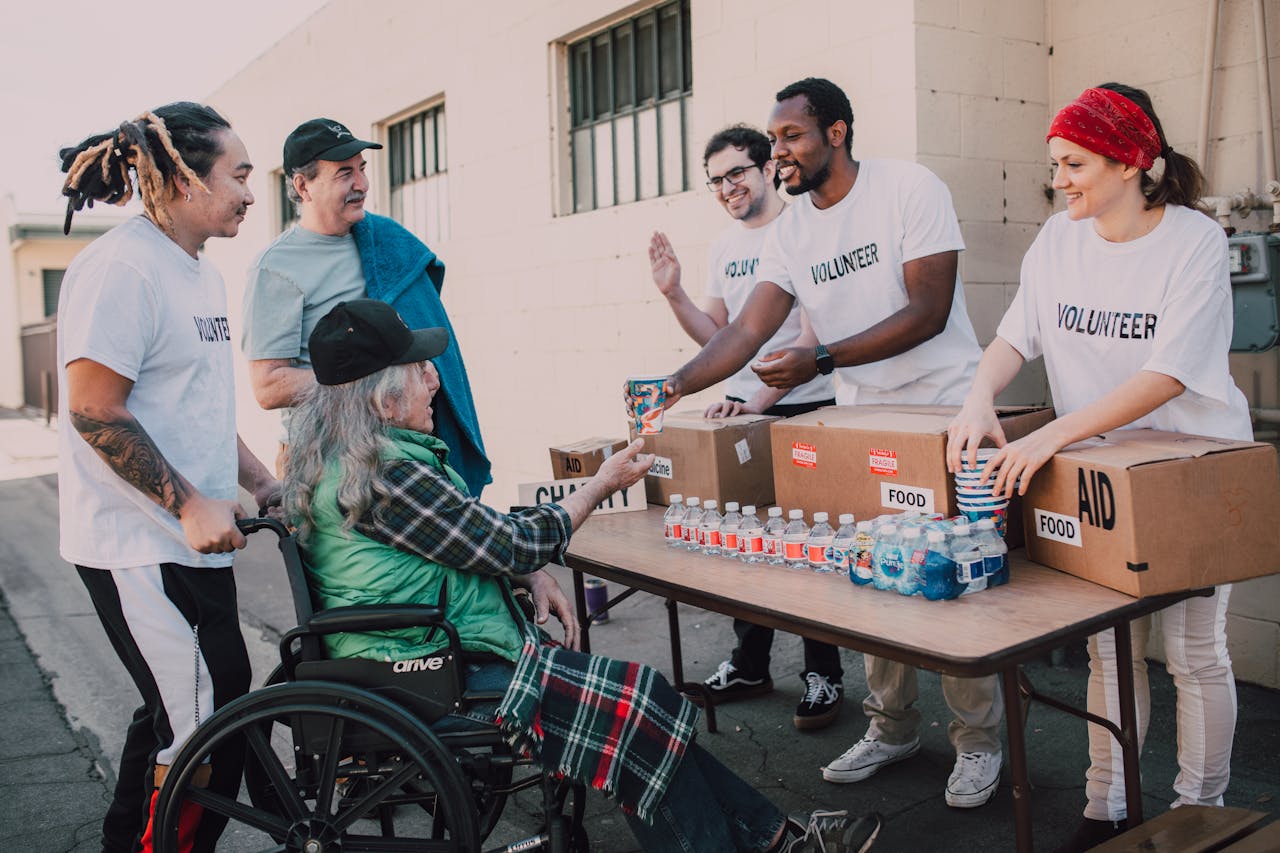 services-03 Volunteers distribute bottled water and supplies to diverse individuals in an outdoor setting, showcasing community support.